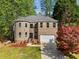 Charming brick home featuring a two-car garage, well-manicured lawn, and mature trees at 6960 Dockbridge Way, Stone Mountain, GA 30087