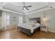 Elegant main bedroom boasts tray ceilings, ceiling fan and hardwood flooring at 11570 Dunhill Place Dr, Johns Creek, GA 30005