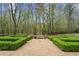 Backyard with manicured hedges, gravel path, and metal garden sculpture at 440 Old Homestead Trl, Johns Creek, GA 30097