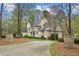 Charming stone home with a circular driveway, stone entry pillars, and lush landscaping, offering a grand approach at 440 Old Homestead Trl, Johns Creek, GA 30097