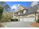 Elegant stone home with a black roof, multiple garages, and manicured landscaping at 440 Old Homestead Trl, Johns Creek, GA 30097