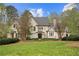 Elegant stone home with a manicured lawn, mature trees, and classic architectural details, creating a stunning curb appeal at 440 Old Homestead Trl, Johns Creek, GA 30097