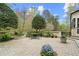 Beautiful brick patio with lush landscaping, a stone wall and dining area, perfect for outdoor entertaining at 440 Old Homestead Trl, Johns Creek, GA 30097