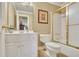 Well-lit bathroom featuring a vanity with a white countertop, a toilet, and a shower with a gold-trimmed glass door at 8385 Sentinae Chase Dr, Roswell, GA 30076