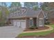 A three car garage featuring stone and stucco exterior, and manicured landscaping at 8385 Sentinae Chase Dr, Roswell, GA 30076