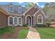 Elegant home featuring a stone facade, arched windows, dormers, and a beautifully landscaped yard at 8385 Sentinae Chase Dr, Roswell, GA 30076