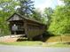 Rustic covered bridge over a calm river surrounded by lush greenery and mature trees on a sunny day at 6040 Carriage Dr, Cumming, GA 30028