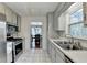 Kitchen with stainless steel appliances, white cabinets, tiled floors, and dining area access at 6040 Carriage Dr, Cumming, GA 30028