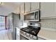 Well-lit kitchen featuring stainless steel appliances, light cabinets, and white tiled floors at 6040 Carriage Dr, Cumming, GA 30028