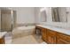 Bright bathroom featuring a bathtub, glass-enclosed shower, and double sink at 12120 Dancliff Trce, Alpharetta, GA 30009