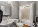 Elegant bathroom with a pedestal sink, decorative mirror, and a combined shower and bathtub at 12120 Dancliff Trce, Alpharetta, GA 30009