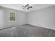 A basic bedroom featuring gray walls and gray carpet with a ceiling fan and window at 570 Bell Se Rd, Conyers, GA 30094