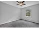 An empty bedroom featuring gray walls and gray carpet with a ceiling fan and a window at 570 Bell Se Rd, Conyers, GA 30094