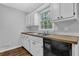 A view of the kitchen sink with wood countertop, white cabinets, and a black dishwasher at 570 Bell Se Rd, Conyers, GA 30094