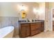 Luxurious bathroom featuring double vanity, soaking tub, modern fixtures, and tile flooring at 1630 Chadwick Mill Ln, Lawrenceville, GA 30043