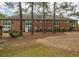 Property backyard showing trees, green grass, and a partial view of a brick building at 310 Brittany Ct, Duluth, GA 30096