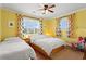 Bright bedroom with two beds, wood floors, ceiling fan, and colorful curtains at 2984 Bayard St, East Point, GA 30344