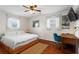 Bright bedroom with wood floors, ceiling fan, a queen-sized bed, and a desk with a blue chair at 2984 Bayard St, East Point, GA 30344