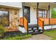 Welcoming front porch with decorative wooden railing, black front door, stone accents, and fresh landscaping at 10386 Wisteria Ln, Jonesboro, GA 30238