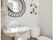 Updated half bathroom featuring modern fixtures, a pedestal sink, and a decorative round mirror at 5888 Riverstone Cir # 15, Atlanta, GA 30339