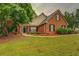 Charming brick home featuring a manicured lawn, mature trees, and a welcoming front entrance at 1917 Kevin Dr, Conyers, GA 30013