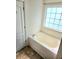 Bathroom featuring an oval soaking tub and a window offering natural light at 204 Millpond Pkwy, Villa Rica, GA 30180