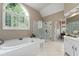 Bright bathroom featuring a large garden tub beneath a large window and glass enclosed shower at 205 Wellesley Ct, Woodstock, GA 30189