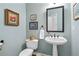 Half bathroom featuring a pedestal sink, decorative mirror, and a traditional-style toilet at 205 Wellesley Ct, Woodstock, GA 30189