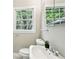 Neutral toned bathroom featuring a white sink, toilet, mirror, and a window with views to the exterior at 2488 Glendale Se Cir, Smyrna, GA 30080