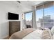 Relaxing bedroom features a modern dresser, large window with city views and access to a balcony, and a mirror at 855 Peachtree Ne St # 2706, Atlanta, GA 30308
