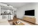 Open-concept living room and kitchen features modern decor, white cabinets, stainless steel appliances, and sleek bar stools at 855 Peachtree Ne St # 2706, Atlanta, GA 30308