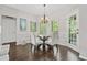 Bright dining room features a modern chandelier, dark floors, and a glass table surrounded by four upholstered chairs at 155 Glenside Ln, Duluth, GA 30097