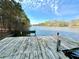 Picturesque view from a wooden dock overlooking a serene lake, with lush trees and a clear blue sky at 123 Wildwood Dr, Temple, GA 30179