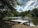Scenic view of a tranquil lake with a wooden dock, surrounded by lush greenery and a cloudy sky at 123 Wildwood Dr, Temple, GA 30179
