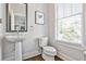 Powder room with a pedestal sink, toilet, and a bright window at 125 Sidney St, Marietta, GA 30060