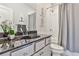 Bathroom featuring a shower with gray tiled walls, black countertop, and white cabinets at 125 Sidney St, Marietta, GA 30060