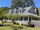 Charming home featuring light blue siding, white trim, dormer windows, a brick chimney, and a welcoming front porch at 5167 Manitu Sw Ct, Lilburn, GA 30047