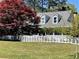 Home with dormer windows and mature trees behind the white picket fence at 5167 Manitu Sw Ct, Lilburn, GA 30047