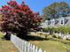 Quaint home featuring a lush lawn, a striking red maple tree, and a classic white picket fence at 5167 Manitu Sw Ct, Lilburn, GA 30047