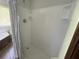 A clean white shower stall with a shower head and shelving on the back wall at 5167 Manitu Sw Ct, Lilburn, GA 30047