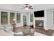 A cozy living room featuring a fireplace, ceiling fan, and many windows for ample natural light and wood flooring at 174 Vandiver Ct, Acworth, GA 30101