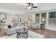 A bright living room featuring hardwood flooring, comfortable seating, a ceiling fan, and large windows, all bathed in natural light at 174 Vandiver Ct, Acworth, GA 30101