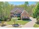 Beautiful two-story brick home with a well-manicured lawn and a long driveway surrounded by lush greenery at 205 Northampton Ct, Canton, GA 30115
