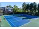 Bright blue tennis courts with green borders, benches and lush trees in a lovely community at 1207 Promontory Path, Marietta, GA 30062