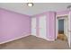 Bright bedroom featuring neutral carpet, lavender walls, and white doors at 1635 Round Rd, Grayson, GA 30017