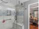 Modern shower with geometric tile, a bench, and glass doors; view of the primary bedroom at 219 Riverbrook Ct, Mcdonough, GA 30252