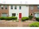 Charming townhouse featuring a red front door and well-manicured green shrubbery at 104 Holcomb Ferry Rd, Roswell, GA 30076