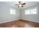 Cozy bedroom featuring rich hardwood floors, a ceiling fan, and plenty of natural light from two windows at 605 Rocky Branch Rd, Villa Rica, GA 30180