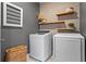 This laundry room showcases front load machines, floating wood shelves, and a modern gray color palette at 7515 Cordery Rd, Cumming, GA 30040