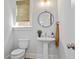 Cozy powder room featuring a pedestal sink, round mirror, and a neutral color palette at 7515 Cordery Rd, Cumming, GA 30040